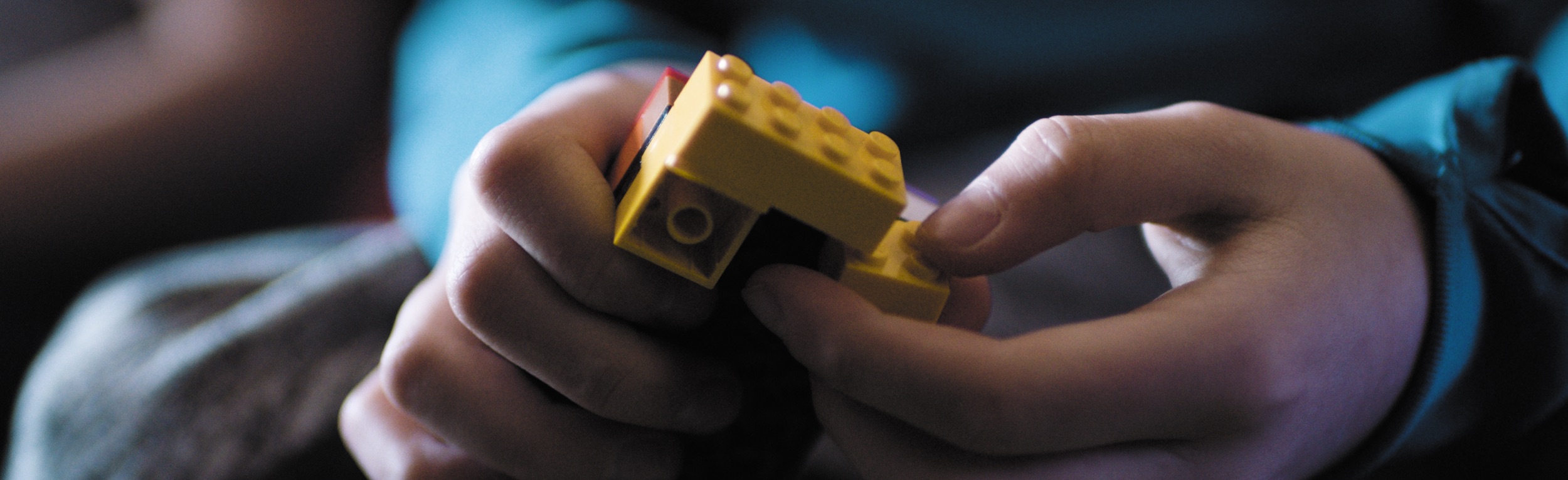 Två händer som bygger med Lego